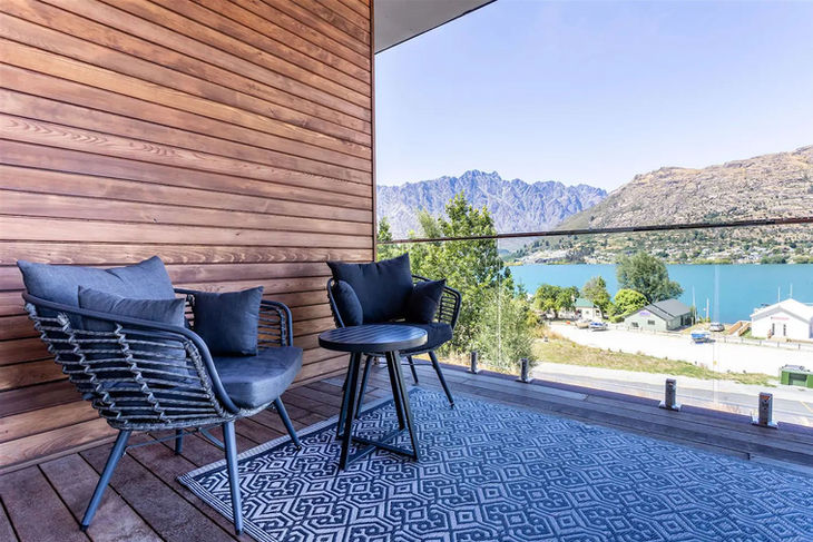 two chairs and a table on a balcony overlooking a lake