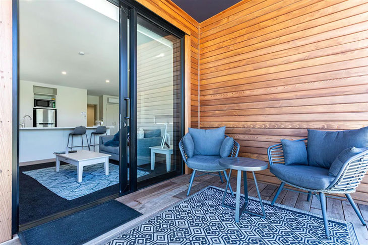 a patio with chairs and a table in front of a sliding glass door