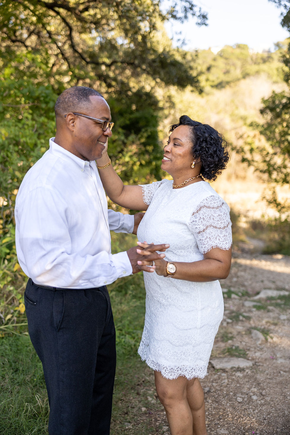 a Black woman in a white dress putting her hand on her fiancé's cheek