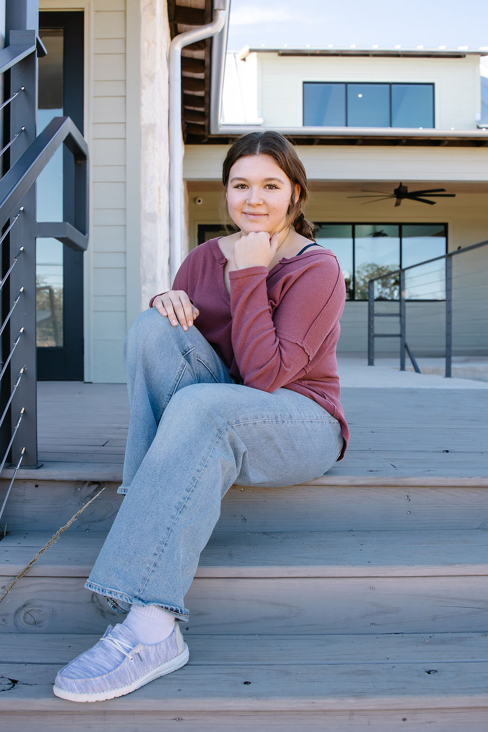 A senior photo of a teenage girl on stairs smiling softly