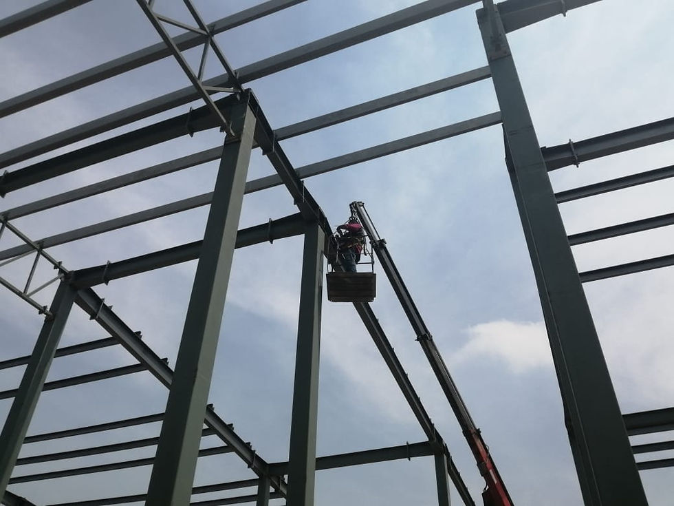 Inspector de ICE realizando evaluación de uniones soldadas en estructura metálica de nave industrial