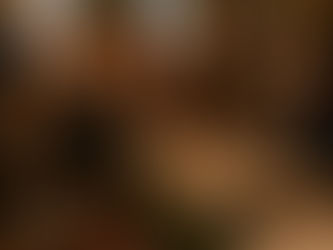 A modern waitress with curly auburn hair, wearing black capris, a tank top, and red sneakers, squints at the U.S. Constitution in a candlelit colonial room as Benjamin Franklin offers her his eyeglasses, surrounded by founding fathers.