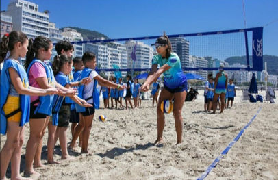 Menina ensinando vôlei para crianças na praia com rede de vôlei