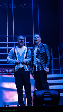 Two ZEST men sing passionately on stage in moody blue light for Dogfight the musical, November 2024.