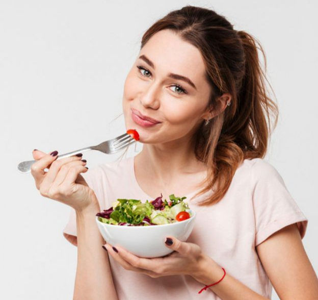 Woman smiling while holding a bowl of healthy salad, representing customized diet plan at Nova Aesthetic Clinic