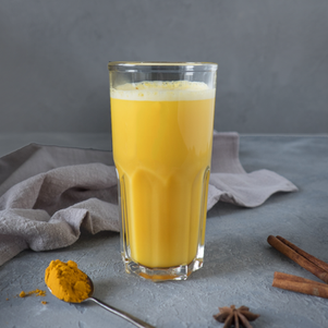 Vaso de cristal con Golden Milk Chai color amarillo intenso decorado con canela.