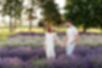A man and woman hold hands in a lavender field