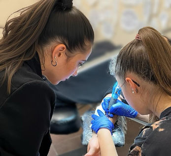 Zwei Frauen tätowieren einen Arm Tattoo-Studio, blaue Handschuhe und Nadel