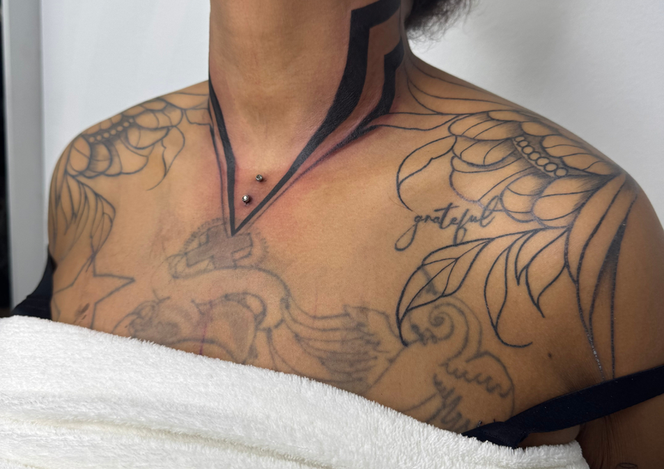 Person mit komplexen floralen und geometrischen Tattoos auf Brust und Nacken.