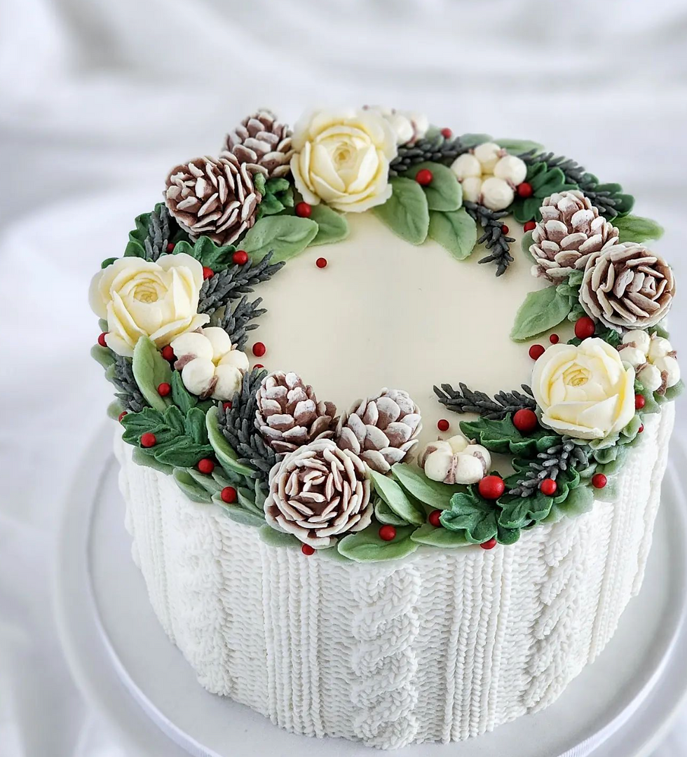 Cable knit white cake with wreath design on top with pine cones, roses and holly berries