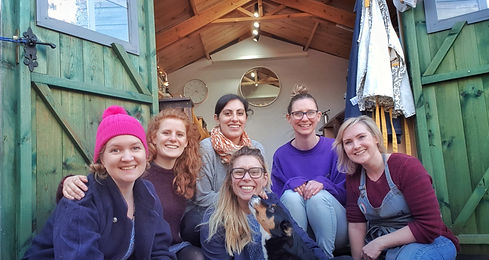 Students sit outside the studio smiling.