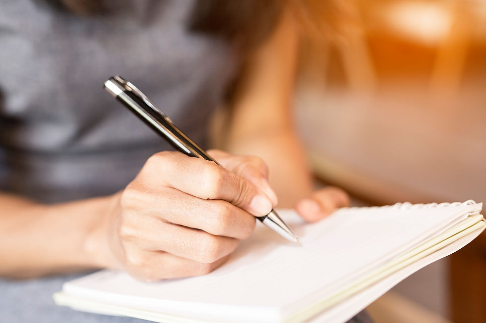 a woman writing in a notebook with a pen