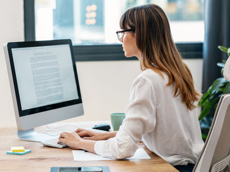 Content marketer writing on a computer in an office