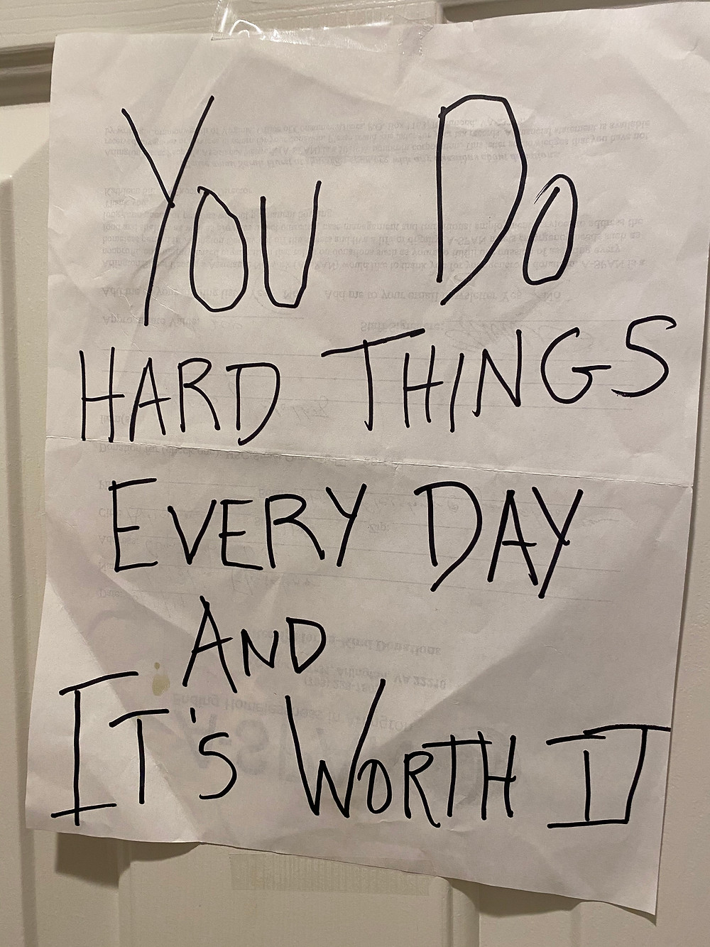 PD: A piece of paper taped to a door. Handwritten on the paper in black pen is the phrase: "You do hard things every day and it's worth it"