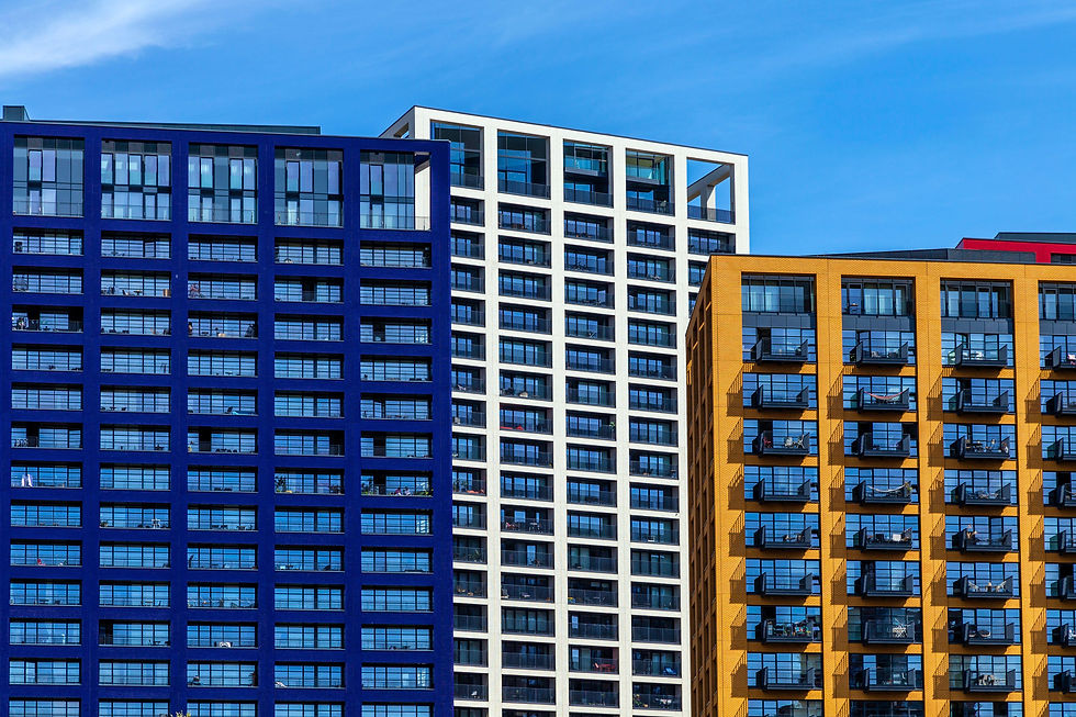 Blue, white, and yellow high-rise buildings at London City Island LCI under a clear blue sky with reflective windows and balconies, creating a modern cityscape.