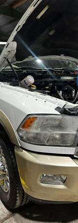 White truck with hood open in shop for repairs and maintenance