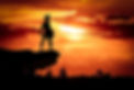 Spartan warrior standing on rock with sunset behind