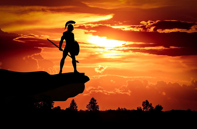 spartan standing on rock with sunset behind