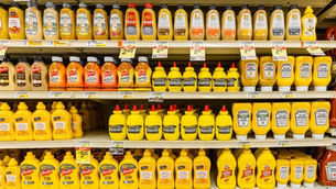 Grocery store shelves filled with assorted mustard bottles
