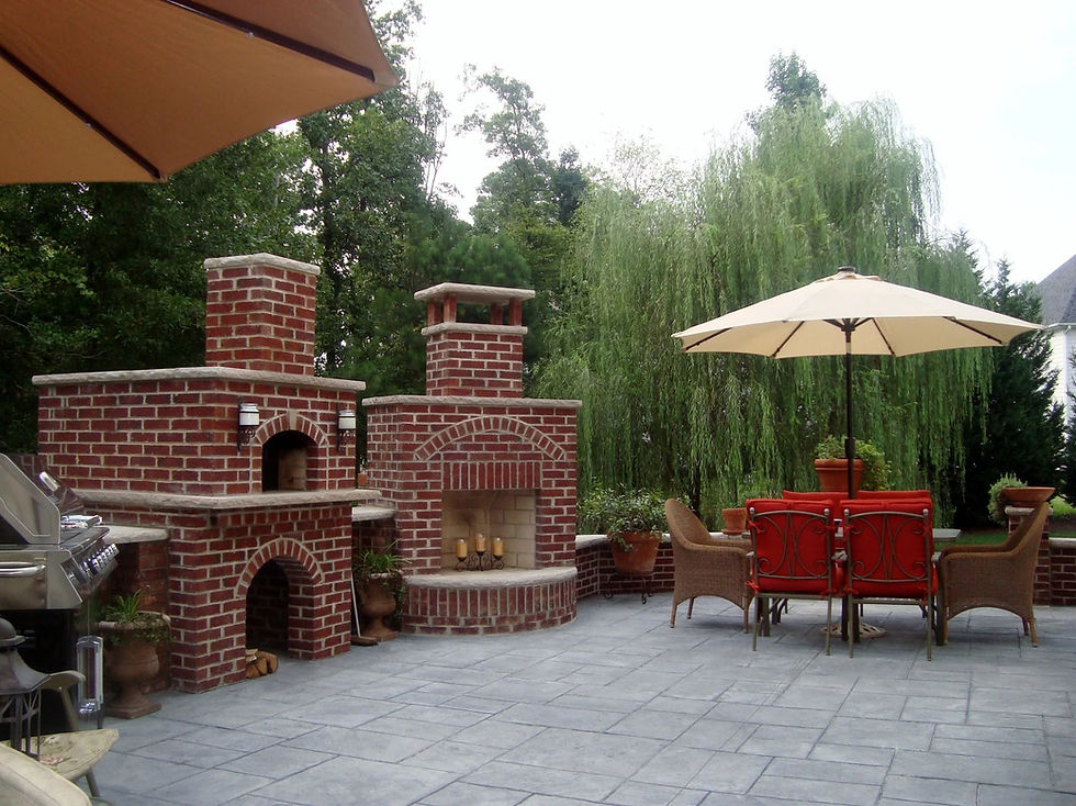 Brick pizza oven and fireplace with seat walls beside a stamped-concrete patio.