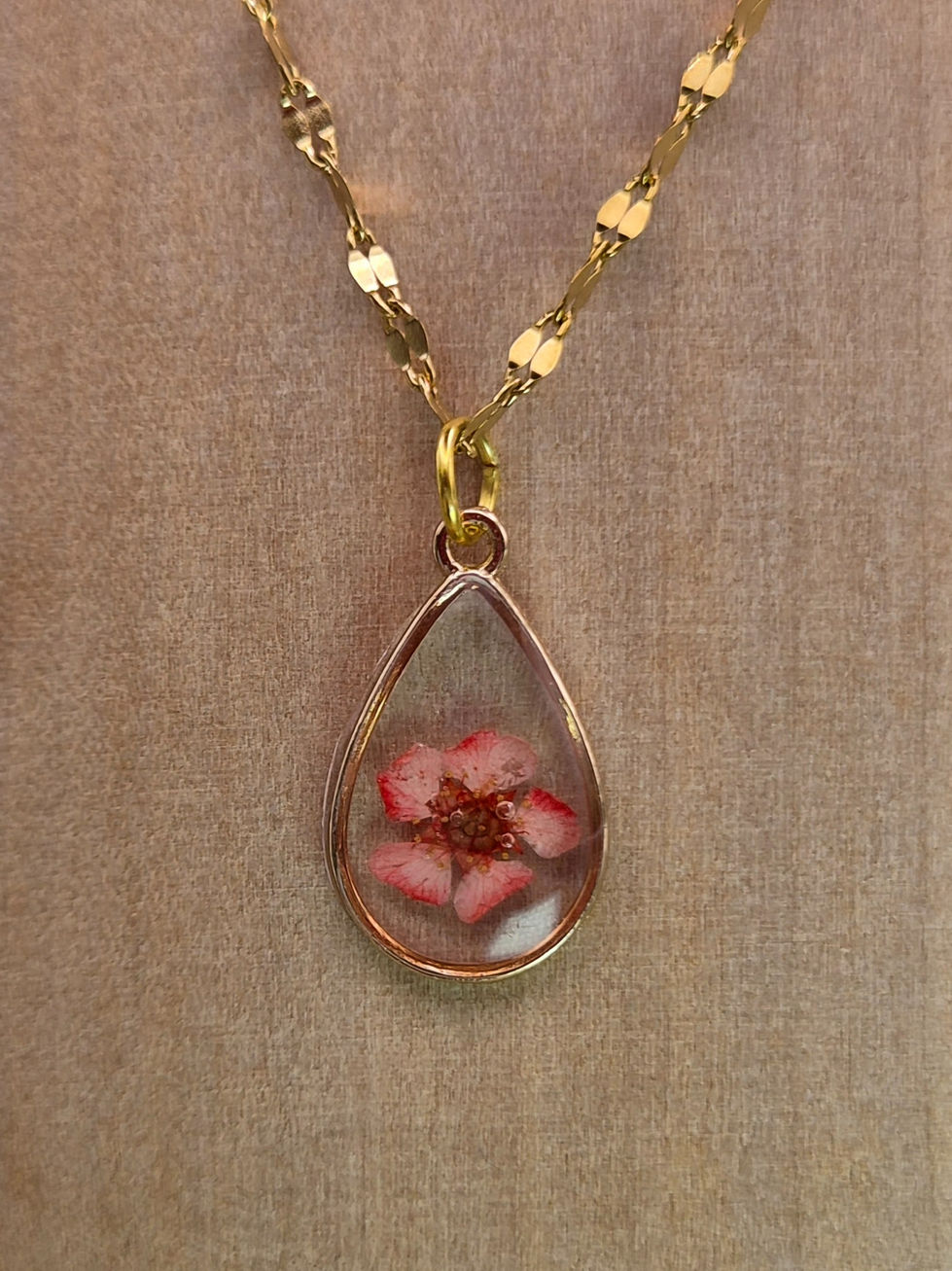 Close view of petite pink pressed flower teardrop resin necklace