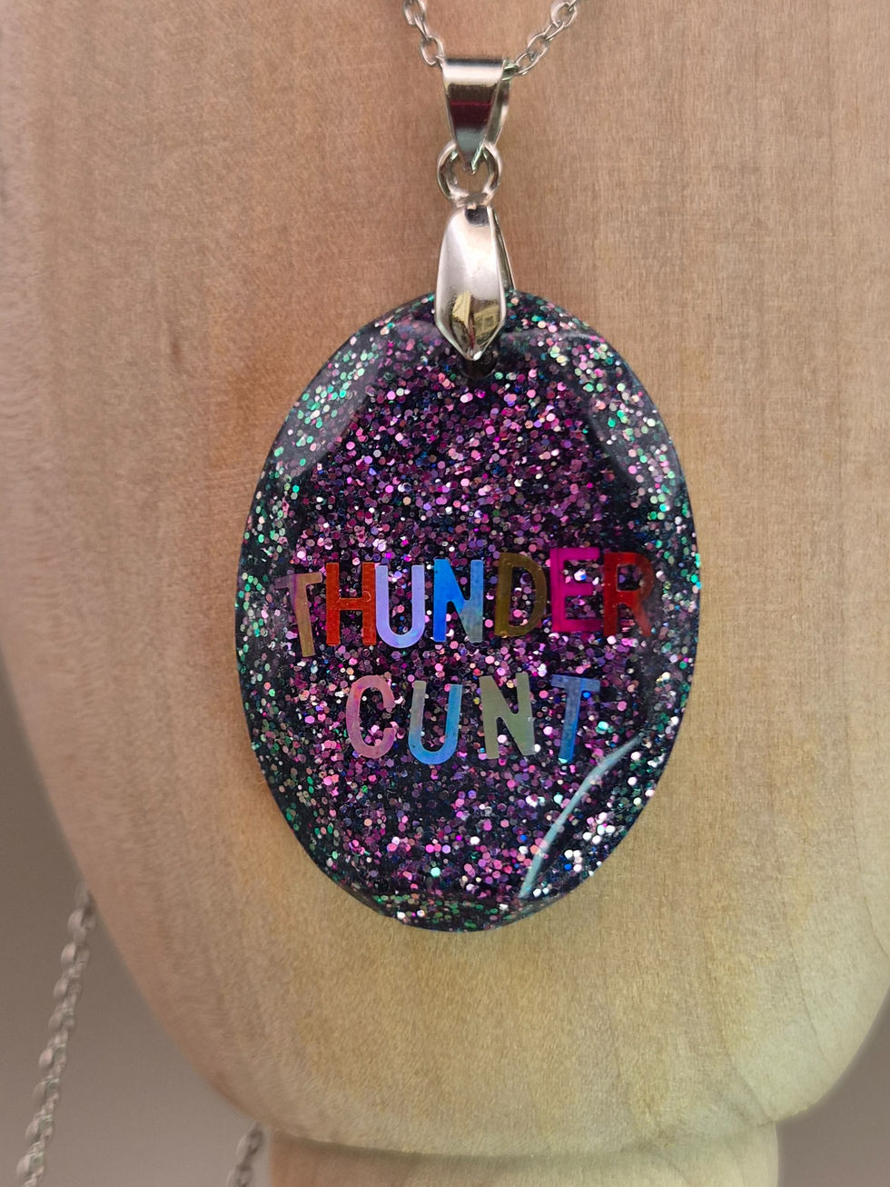 Pink and purple glitter resin necklace reading THUNDER CUNT on a silver-tone chain