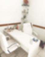 Consultório com mesa branca e cadeiras em sua localização.