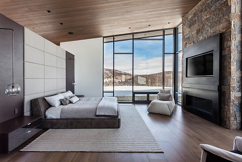 Contemporary home nestled at the base of Shadow Mountain in Aspen, Colorado, illuminated against the twilight sky with its modern glass façade and terraced landscape design.