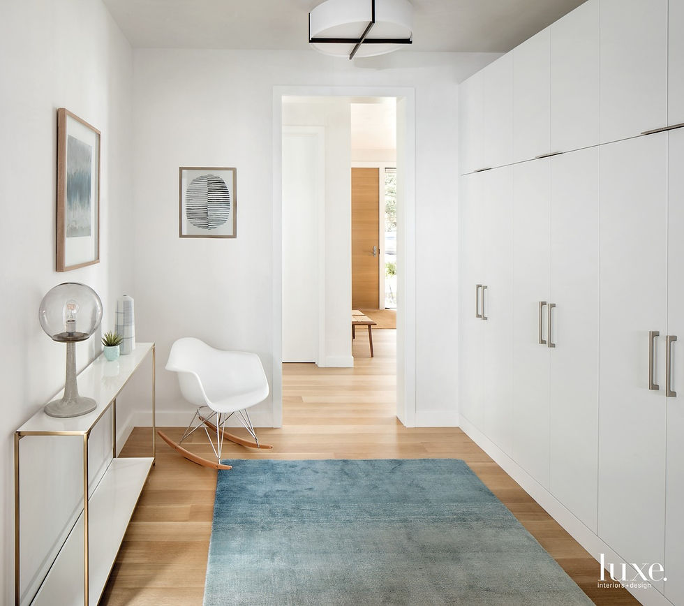 In an Aspen home by architects Seth Hmielowski and Richard Seedorf and designers Joe McGuire and Matthew Tenzin, a hallway has a molded-plastic rocking chair by Charles and Ray Eames and an ombre rug. The console holds a Schoolhouse Electric lamp and a vase by Liz Quan. Cerno's Plura light fixture hangs overhead.