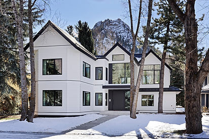 Winter view of a fully renovated Aspen home with white siding, black trim, and gabled roof in the historic Hallam neighborhood