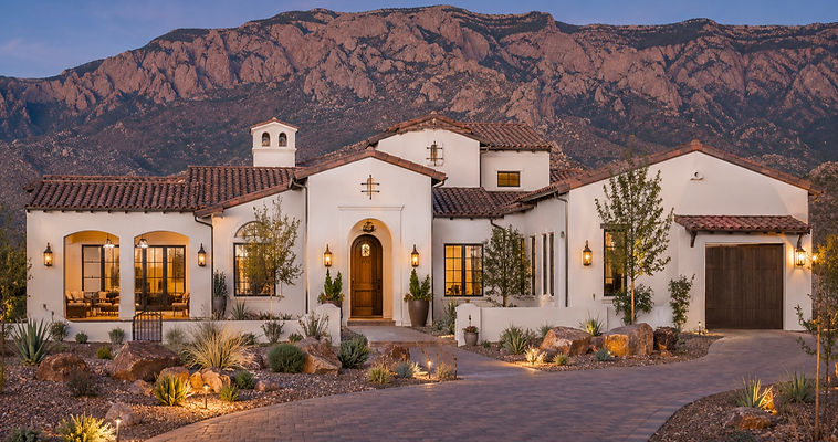 Custom home build Spanish-style house with white stucco, red spanish tile roof at . Desert xeriscape landscaping yard, albuquerque's sandia mountains in the background. new construction single family home in foothills new mexico