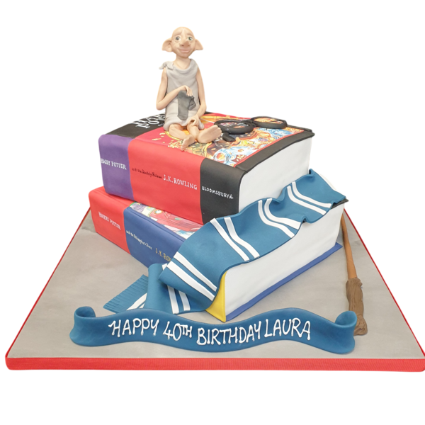 A creative and whimsical Harry Potter themed cake featuring stacked book layers with a fondant figure of Dobbie the house elf on top.