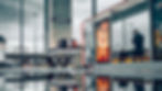 Commuters wait at Warsaw's bustling bus station, surrounded by vibrant outdoor ads