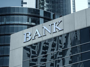 Fachada de um prédio comercial moderno com a palavra BANK em destaque, representando bancos e instituições financeiras.