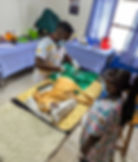 Two veterinarians in colorful scrubs perform surgery on a dog in a clinic with medical tools and supplies in the background at the Uganda SPCA shelter.