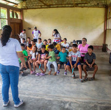A woman facing a sparse room full of young students in a bare classroom in Peru.
