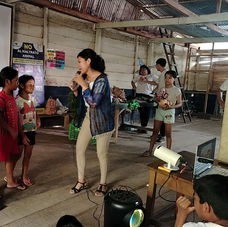 A woman in a classroom talks directly to three children in Peru.