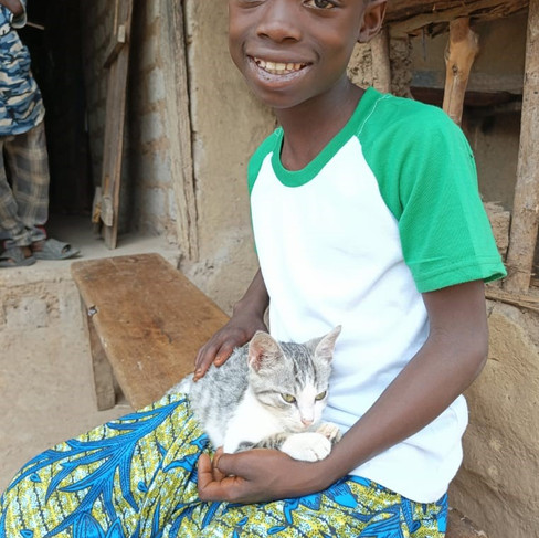 A girl wearing an African print skirt and holding a kitten on her lap in Liberia.