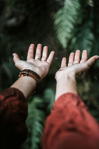 person with outstretched arms feeling the rain