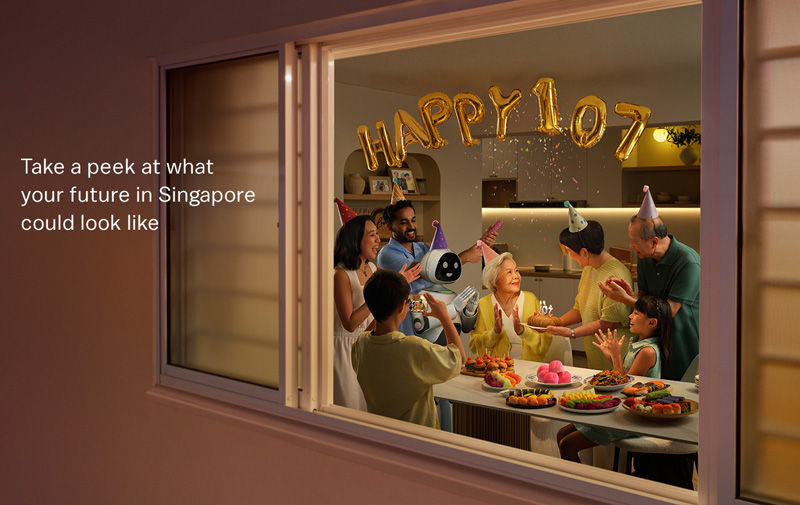 Party scene indoors with diverse people and a robot celebrating. "HAPPY 107" balloons. Confetti falls, festive mood. Text: "Take a peek..."