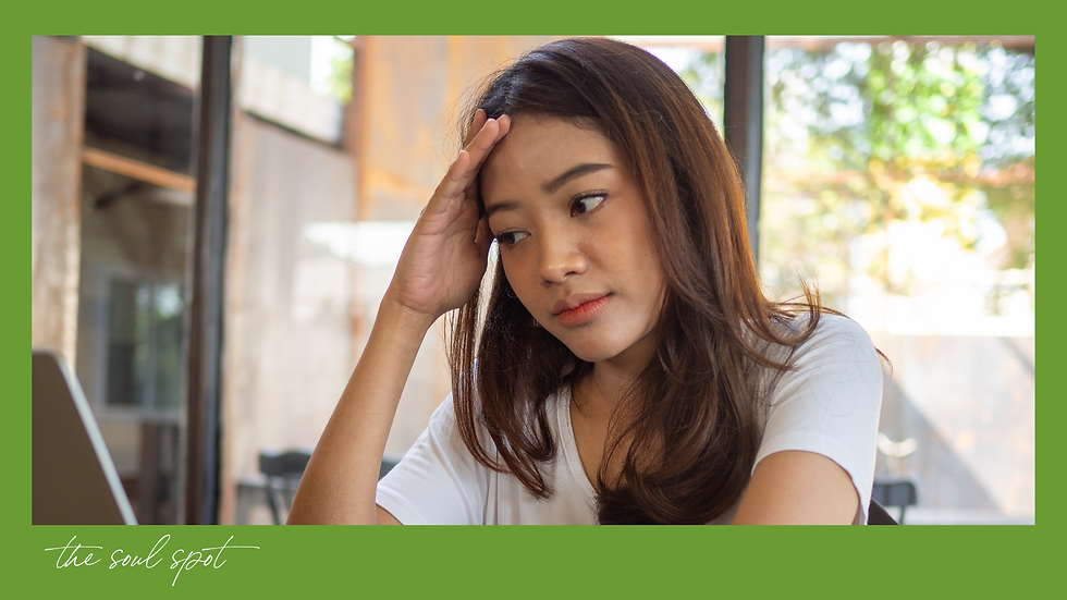 Woman in white shirt looks thoughtful with hand on forehead in bright cafe. Green frame, text "the soul spot." Thoughtful, unsettled expression.