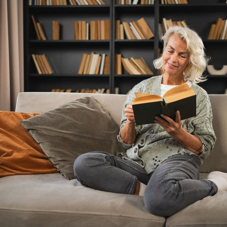 Smiling lady sitting on a sofa reading a book
