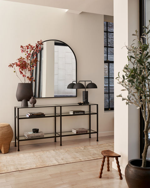 Minimal black earthy console design with half arched mirror.