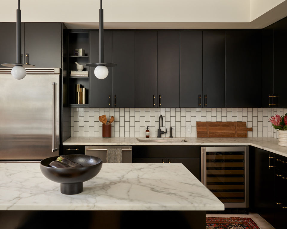 Modern black kitchen design with marble countertops and black cabinets.