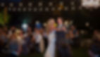 Bride and groom dance at night with guests watching, under beautiful lights.
