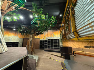 Speels bibliotheekinterieur in Nieuwegein met houten boomelementen, stalen constructies en fantasierijke wandafwerking in oranje en grijstinten