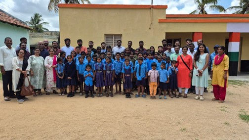 Large group of people posing in front of a building together.