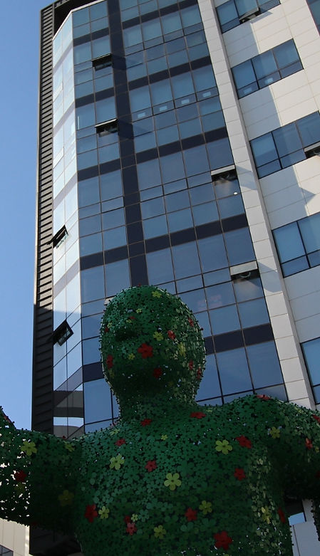 Green plant statue stands tall in front of modern office building Esgtech.