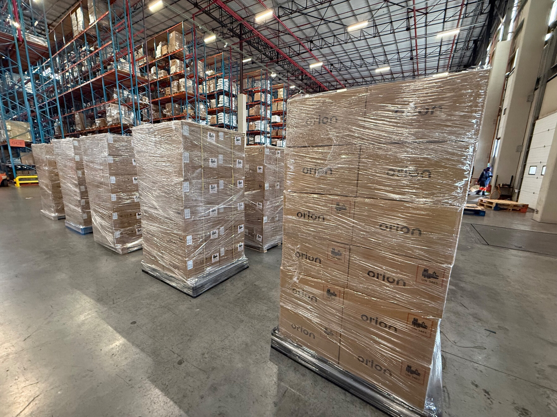 Shrink-wrapped Orion cartons on pallets inside a warehouse.