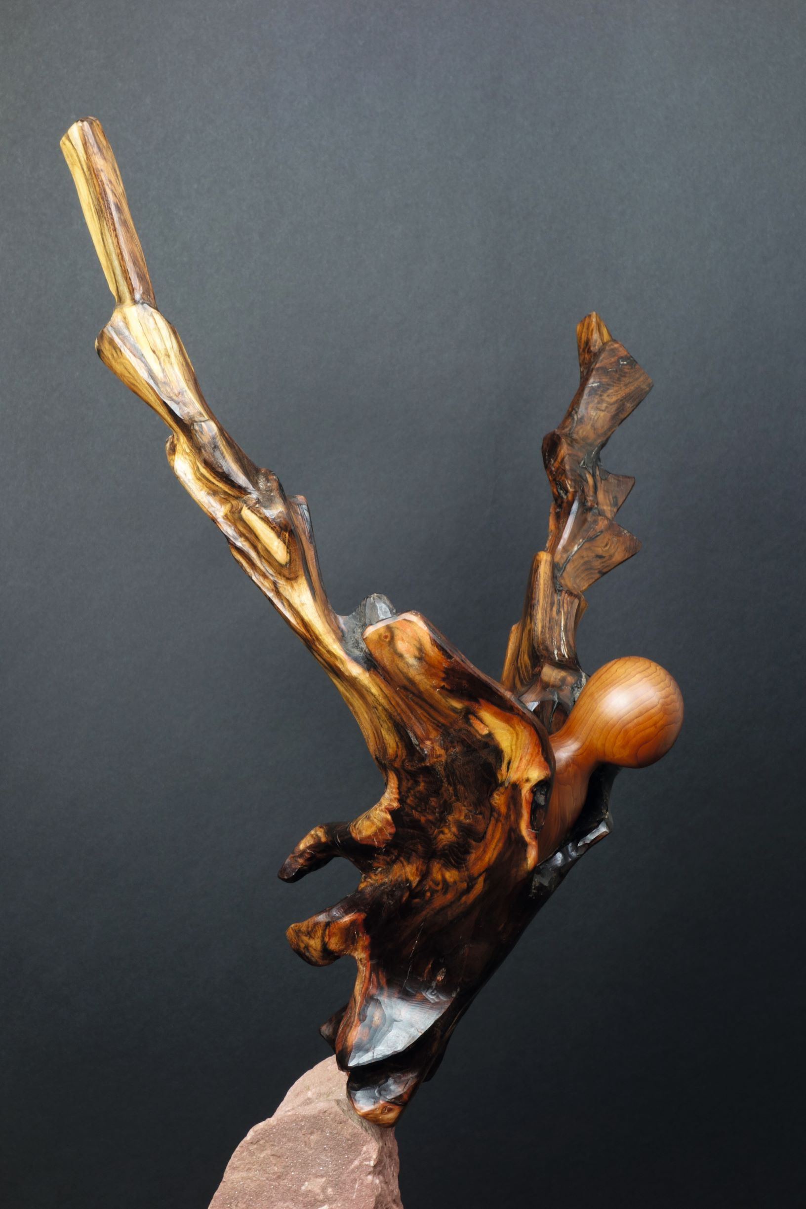 Un homme ailé décolle d’un bloc de pierre. Sculpture en bois et pierre de Christian Delacoux, h 85 cm.